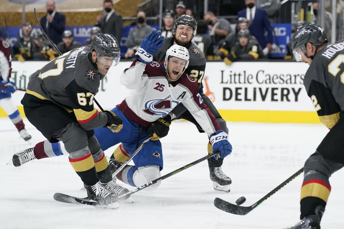 Vegas Golden Knights left wing Max Pacioretty (67) and Vegas Golden Knights defenseman Shea Theodore (27) knock Colorado Avalanche center Nathan MacKinnon (29) to the ice during the third period in Game 3 of an NHL hockey Stanley Cup second-round playoff series Friday, June 4, 2021, in Las Vegas. (AP Photo/John Locher)