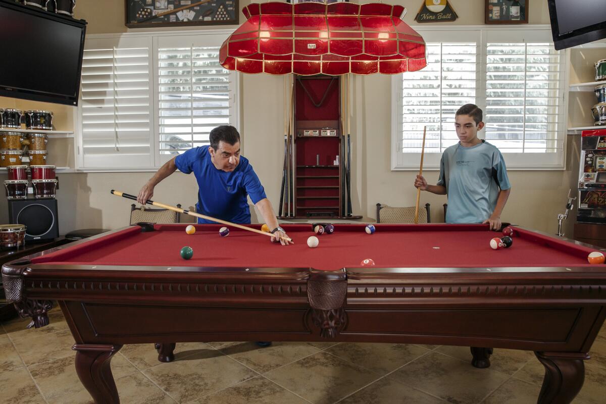 Dr. Shura Alexis Moreno plays pool with his son Gabriel Alejandro Moreno at their home in Alta Loma on Sept. 13, 2021. Dr. Moreno was one of the COVID-19 patients to receive a lung transplant. Photo by Jessica Pons for CalMatters