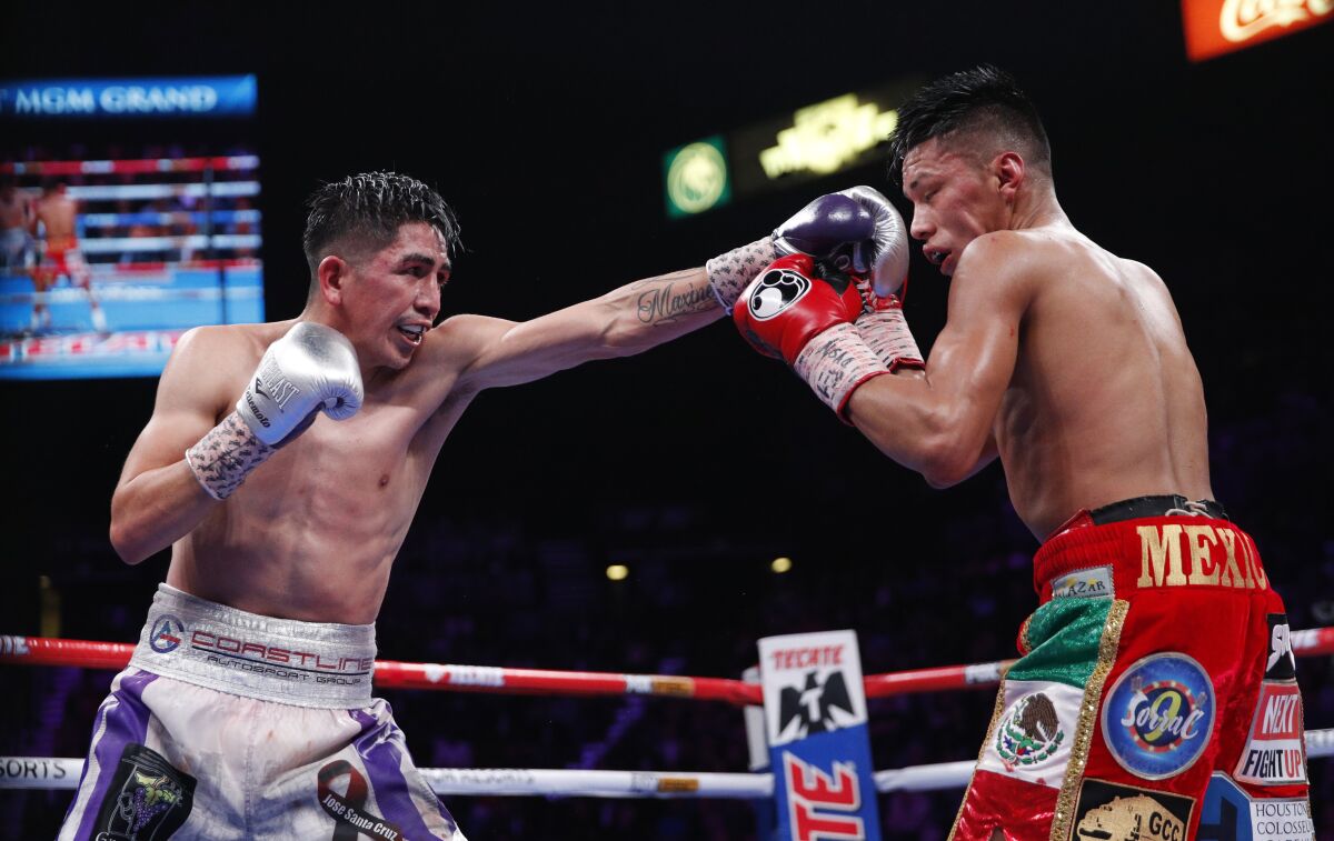 Leo Santa Cruz, left, jabs Miguel Flores during their WBA super featherweight title boxing match in November 2019.