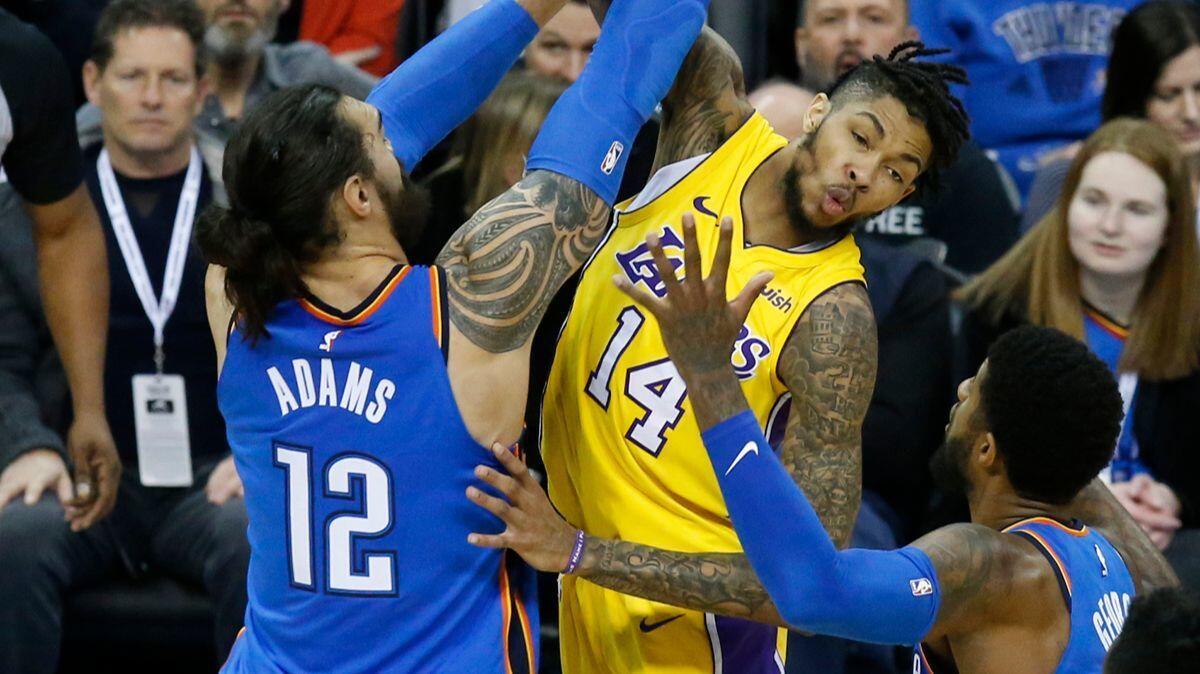 Lakers forward Brandon Ingram (14) passes between Oklahoma City Thunder center Steven Adams (12) and forward Paul George in the first half on Wednesday, Jan. 17, 2018.