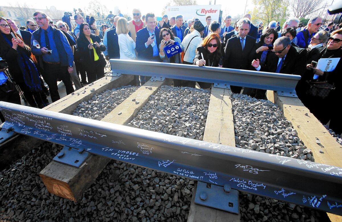 Guests sign segments of railroad track during a January groundbreaking ceremony for a bullet train station in Fresno.