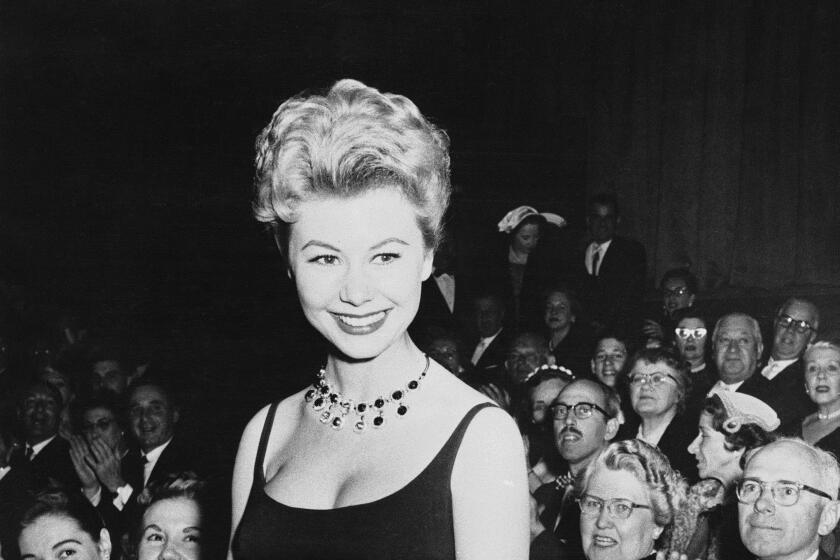 A black and white photo of Mitzi Gaynor in a gown in front of a crowd in 1958