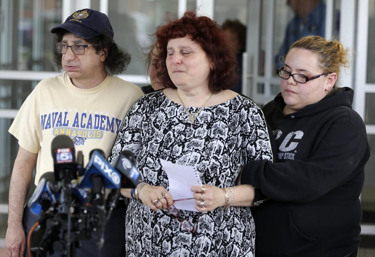 Surrounded by friends and family, Susan Zemser, center, and Howard Zemser, the parents of Naval Academy sophomore Justin Zemser, prepare to speak to the media outside their home in New York on Wednesday.