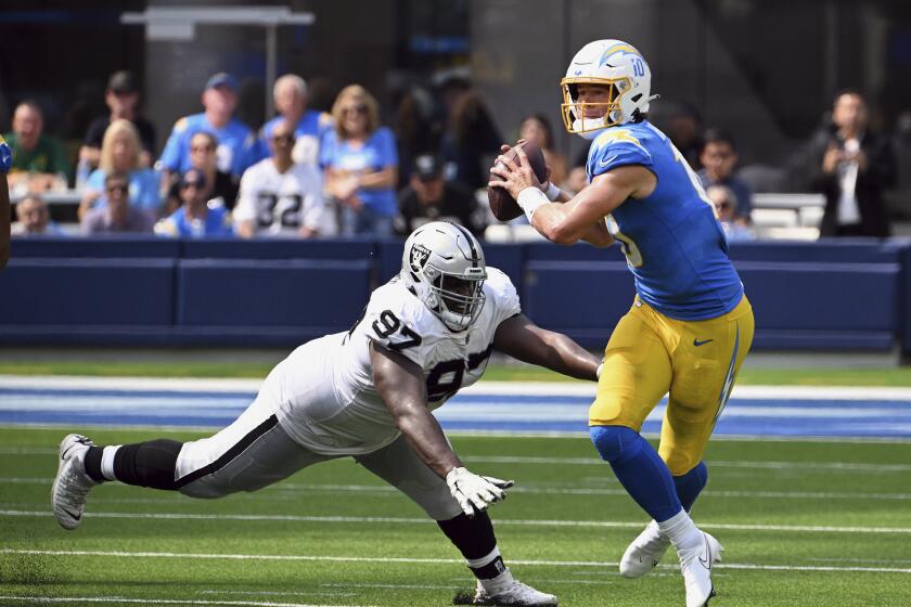 Chargers quarterback Justin Herbert (10) avoids being tackled by  Raider Andrew Billings in 2022. 