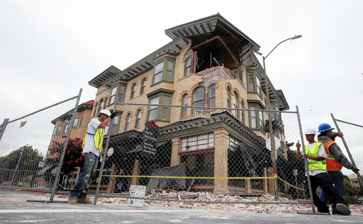 Workmen put up chain-link fencing around a badly damaged building in downtown Napa last year.