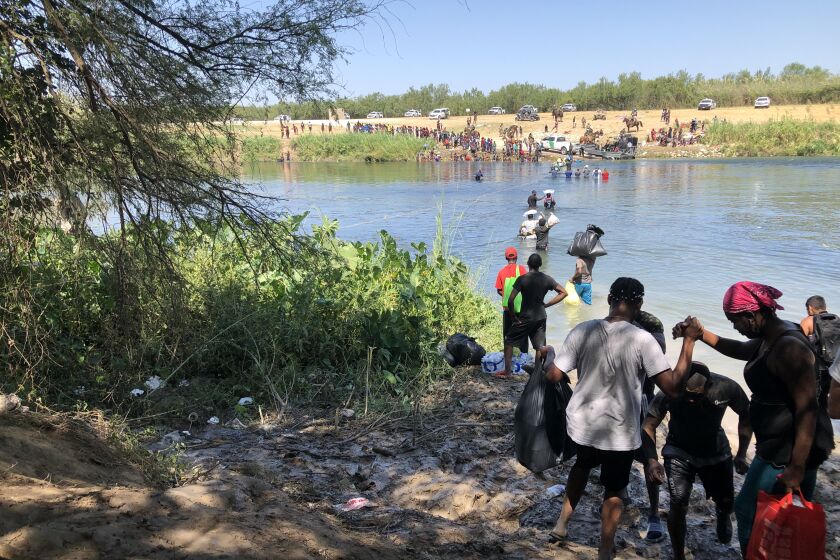 Haitian migrants cross from Del Rio, Texas, to Mexico to get supplies Monday.