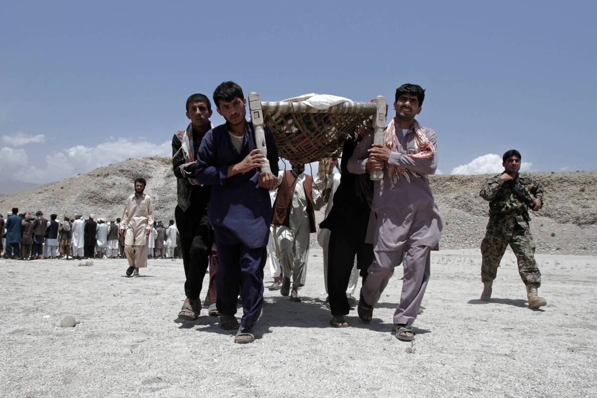 Afghan men carry the bodies of seven civilians killed by a roadside bomb in Laghman province. The family of seven had driven to the mountains to gather firewood, the provincial government said.