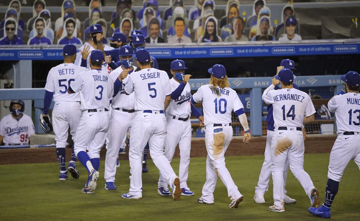 Dodgers players are congratulated by masked members of the coaching staff after a win over the San Francisco Giants 