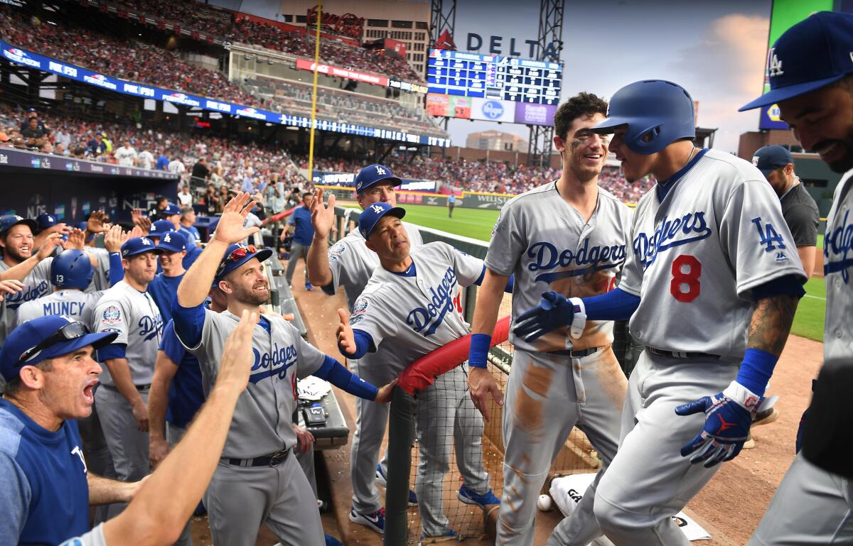 Dodgers Manny Machado is congratulated by teammates and coaches after hitting a three-run home run against the Braves in the 7th inning in Game 4 of the NLDS at SunTrust Park in Atlanta.
