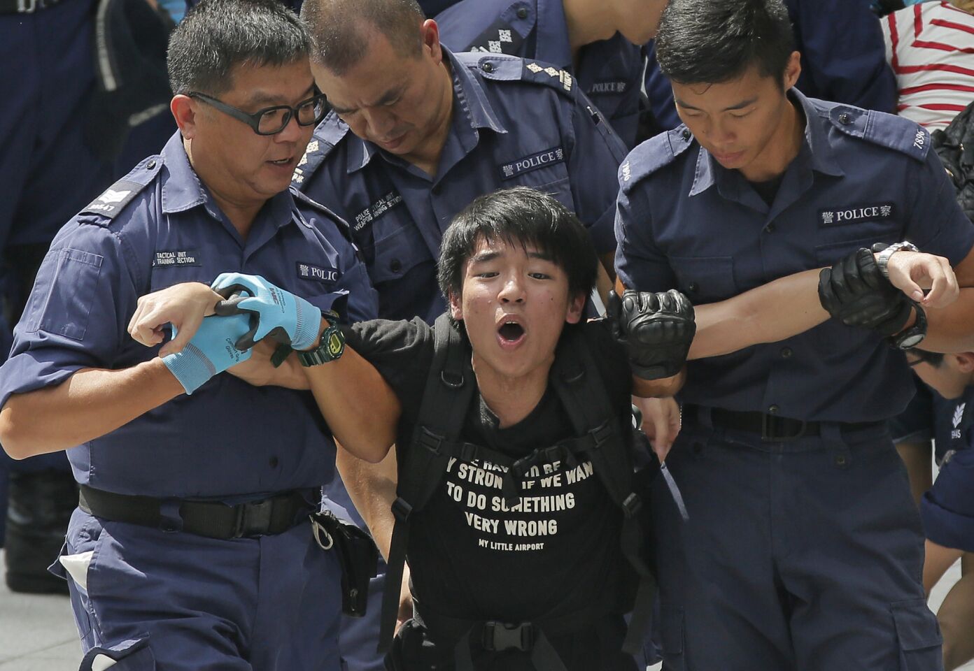 A student is taken away by policemen at the government headquarters in Hong Kong.