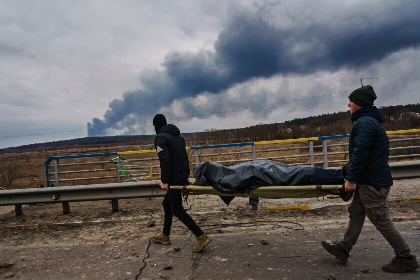 IRPIN, UKRAINE -- MARCH 7, 2022: Ukrainian volunteers help remove a dead civilian body, as Russian forces continue to besiege the residential neighborhood, in Irpin, Ukraine, Monday, March 7, 2022. (MARCUS YAM / LOS ANGELES TIMES)