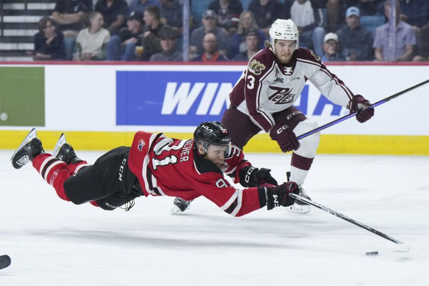 Quebec Remparts' Nathan Gaucher (91) dives for the puck in front of Peterborough Petes' Cam Gauvreau (3) during the first period of a CHL Memorial Cup hockey game Tuesday, May 30, 2023, in Kamloops, British Columbia. (Darryl Dyck/The Canadian Press via AP)