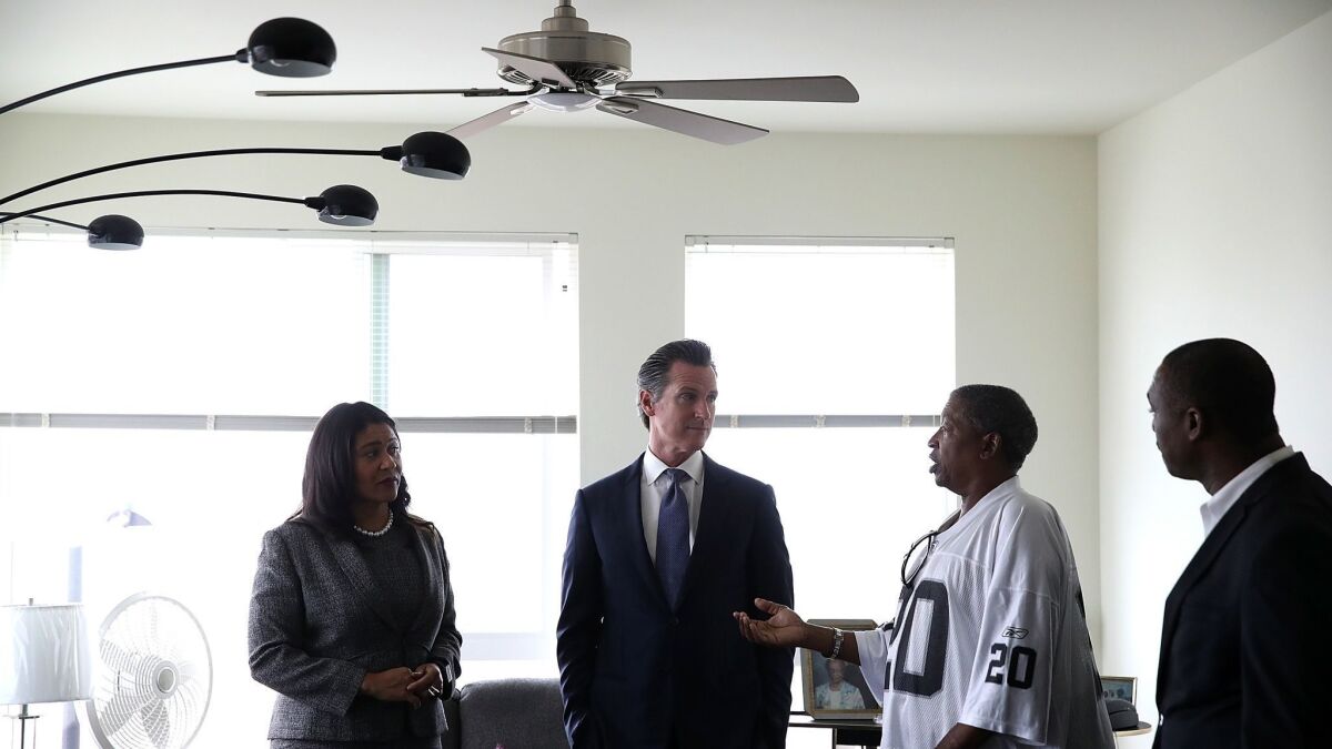California Lt. Gov. and California gubernatorial candidate Gavin Newsom, center, and San Francisco Mayor London Breed, left, talk with a resident as they visit the Alice Griffith Apartments on Aug. 22 in San Francisco.