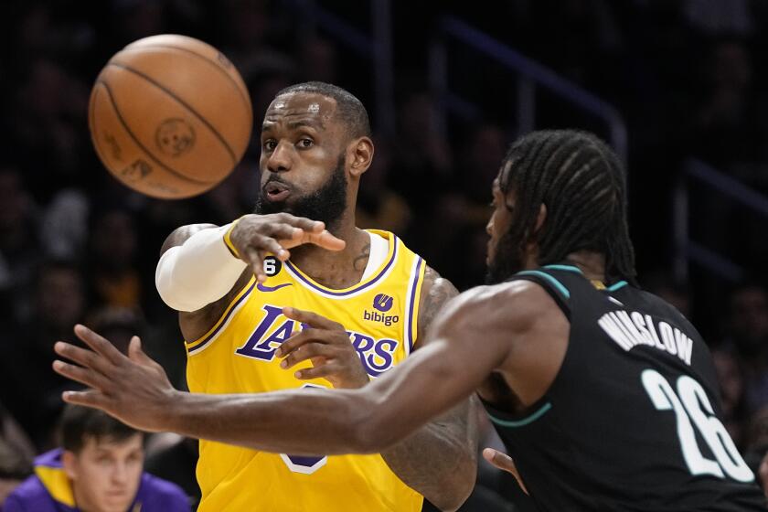 Los Angeles Lakers forward LeBron James, left, passes the ball as Portland Trail Blazers forward Justise Winslow defends during the first half of an NBA basketball game Wednesday, Nov. 30, 2022, in Los Angeles. (AP Photo/Mark J. Terrill)