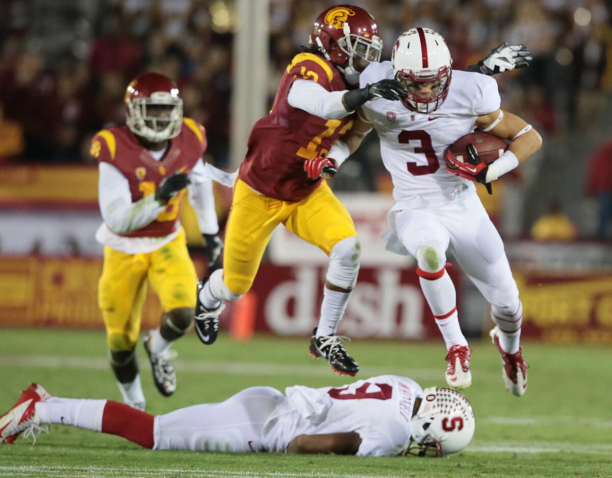Stanford receiver Michael Rector and Trojan defender Kevon Seymour tangle as they leap over Stanford receiver Kodi Whitfield at the Coliseum in November.
