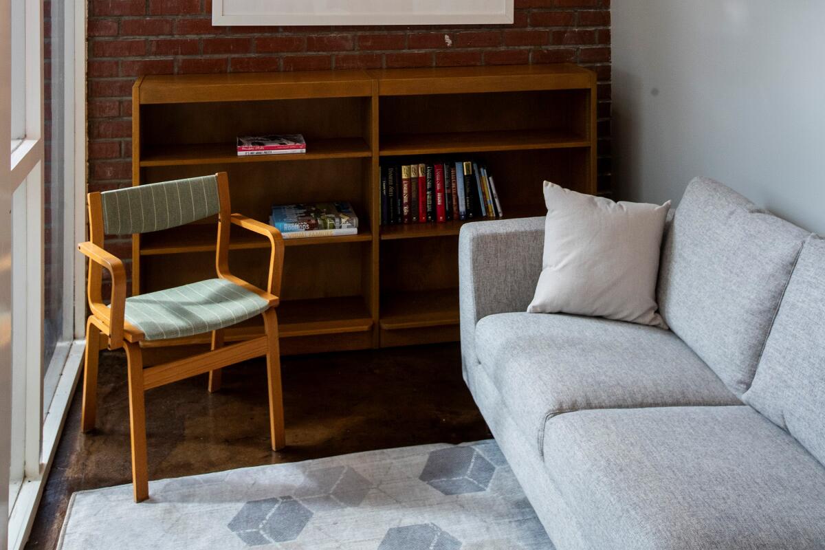 A couch and a chair with a bookshelf.