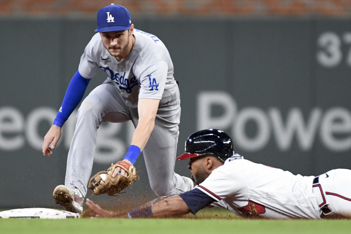 Atlanta's Eddie Rosario dives into second base ahead of the tag by Dodgers second baseman Trea Turner.