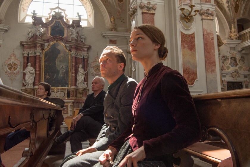 August Diehl, Valerie Pachner and another man and woman sit in the pews of a church in "A Hidden Life."