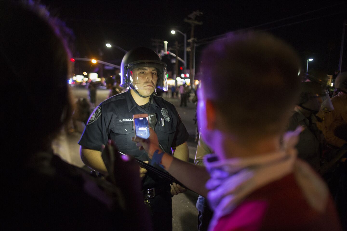 A protester points a cellphone at a police officer after an unlawful assembly is declared near the site where Alfred Olango had been shot by police earlier this week in El Cajon.