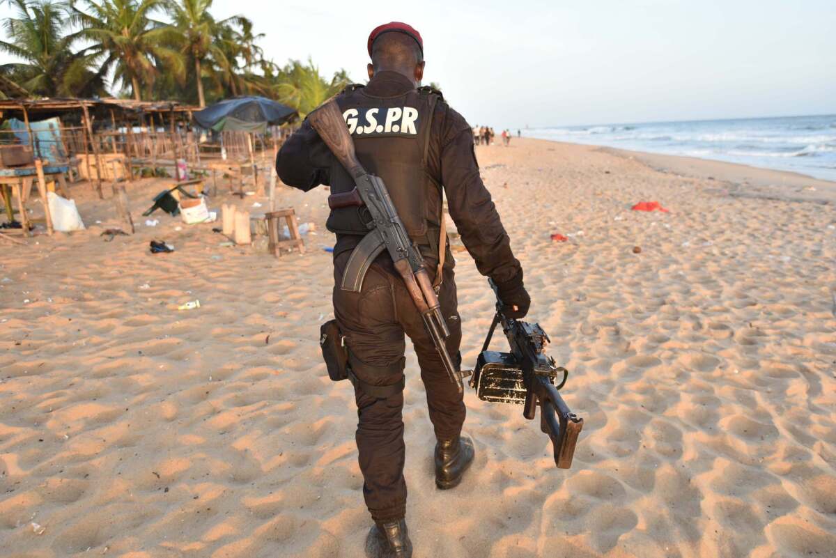 An Ivory Coast soldier carries a machine gun as he walks on the beach resort of Grand Bassam after gunmen went on a shooting rampage. (Sia Kambou / AFP/Getty Images)