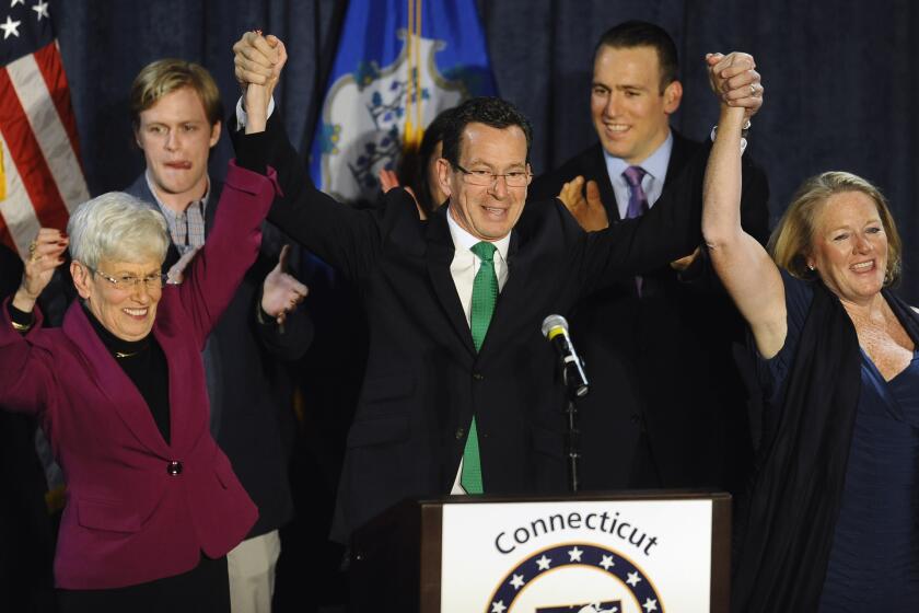 Incumbent Democratic Gov. Dannel P. Malloy, flanked by Lt. Gov. Nancy Wyman, left, and his wife, Cathy, concludes a speech to supporters at his party's rally Wednesday in Hartford, Conn.