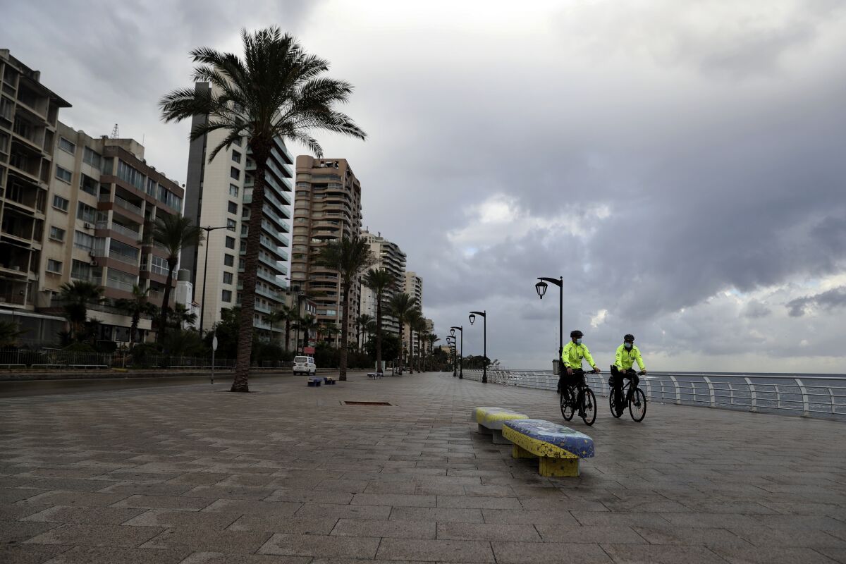 Police bike officers patrol on the empty waterfront promenade as the country starts a new lockdown, in Beirut, Lebanon, Thursday, Jan. 14, 2021. Lebanese authorities began enforcing an 11-day nationwide shutdown and round the clock curfew Thursday, hoping to limit the spread of coronavirus infections spinning out of control after the holiday period. (AP Photo/Bilal Hussein)