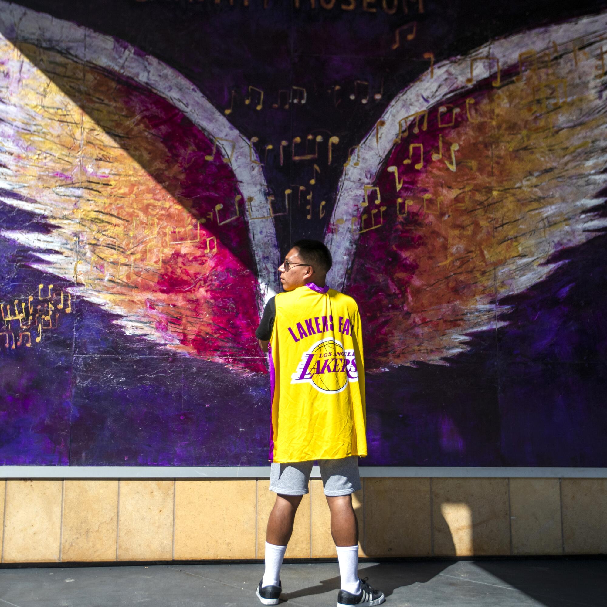 A man stands in front of a mural of angel wings outside the Grammy Museum.
