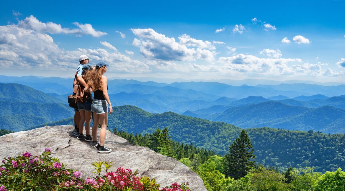 A family stands on a mountain looking out at the  Great Smoky Mountains National Park in North Carolina.