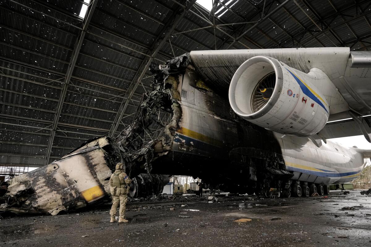 A Ukrainian serviceman walks by the  destroyed Antonov An-225 aircraft 