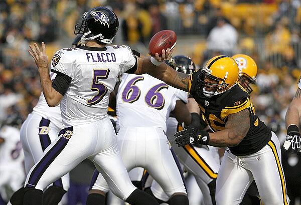 LaMarr Woodley of the Pittsburgh Steelers disrupts the throwing arm of Joe Flacco of the Baltimore Ravens on December 27 at Heinz Field in Pittsburgh, Pennsylvania.