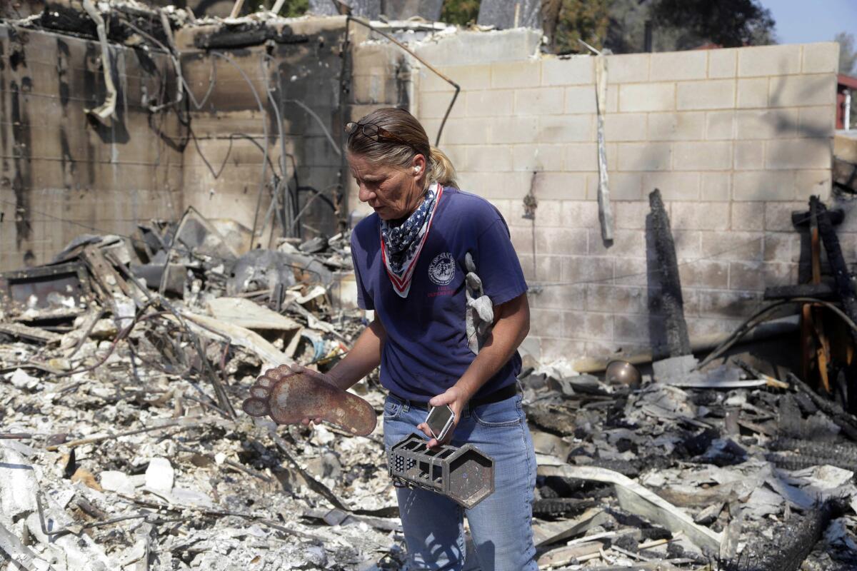 Karrie H. Andrews recupera objetos salvados de entre las ruinas de su casa, el 26 de julio de 2016, tras un incendio que arrasó Santa Clarita, California. (AP Foto/Nick Ut)