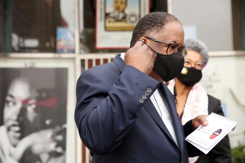LOS ANGELES, CA - NOVEMBER 03: Los Angeles County Supervisor Mark Ridley-Thomas puts his mask on before casting his vote with wife Avis Ridley-Thomas at Hot and Cool Cafe in Leimert Park on Tuesday, Nov. 3, 2020 in Los Angeles, CA. Mark Ridley-Thomas is running against attorney Grace Yoo for a seat on the Los Angeles City Council that is vacated by Councilman Herb Wesson. (Dania Maxwell / Los Angeles Times)