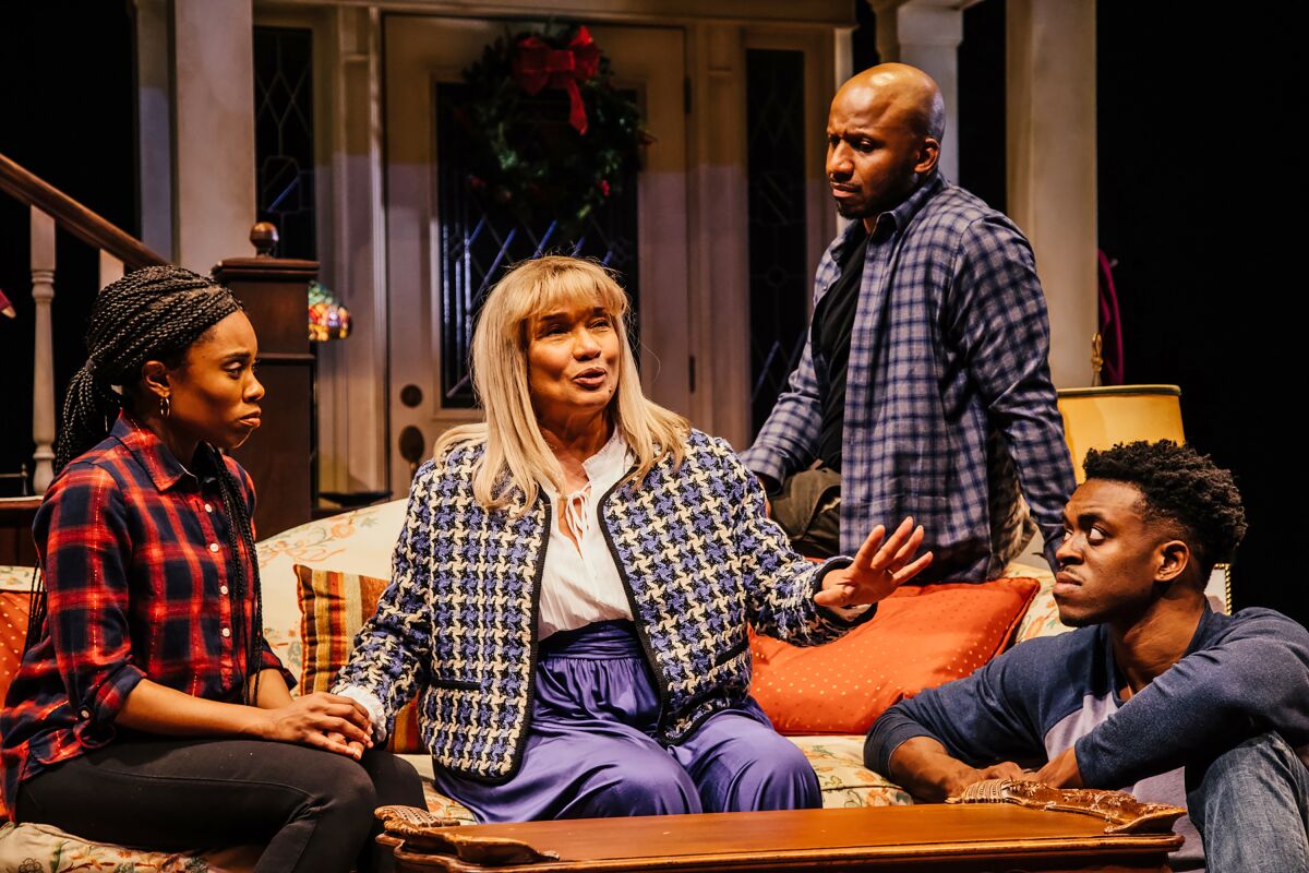 Four actors sit on and around a couch onstage.
