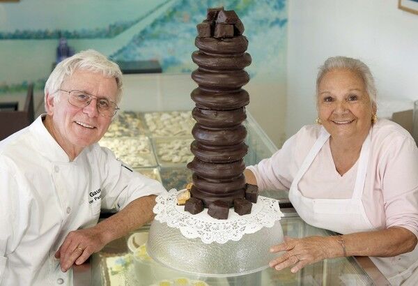 Paul and Irene Gauweiler show off their handiwork: a finished baumkuchen cake covered with chocolate at the Cake Box in Huntington Beach.