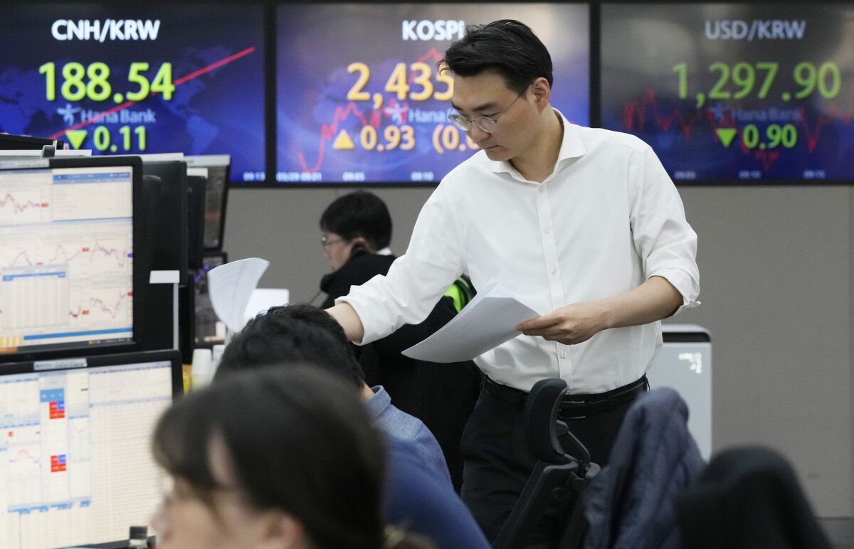 A currency trader works near the screens showing the Korea Composite Stock Price Index (KOSPI), center, and the foreign exchange rate between U.S. dollar and South Korean won, right, at the foreign exchange dealing room of the KEB Hana Bank headquarters in Seoul, South Korea, Wednesday, March 29, 2023. Asian stocks were mixed Wednesday as anxiety about the global financial system began to fade following three high-profile bank failures.(AP Photo/Ahn Young-joon)