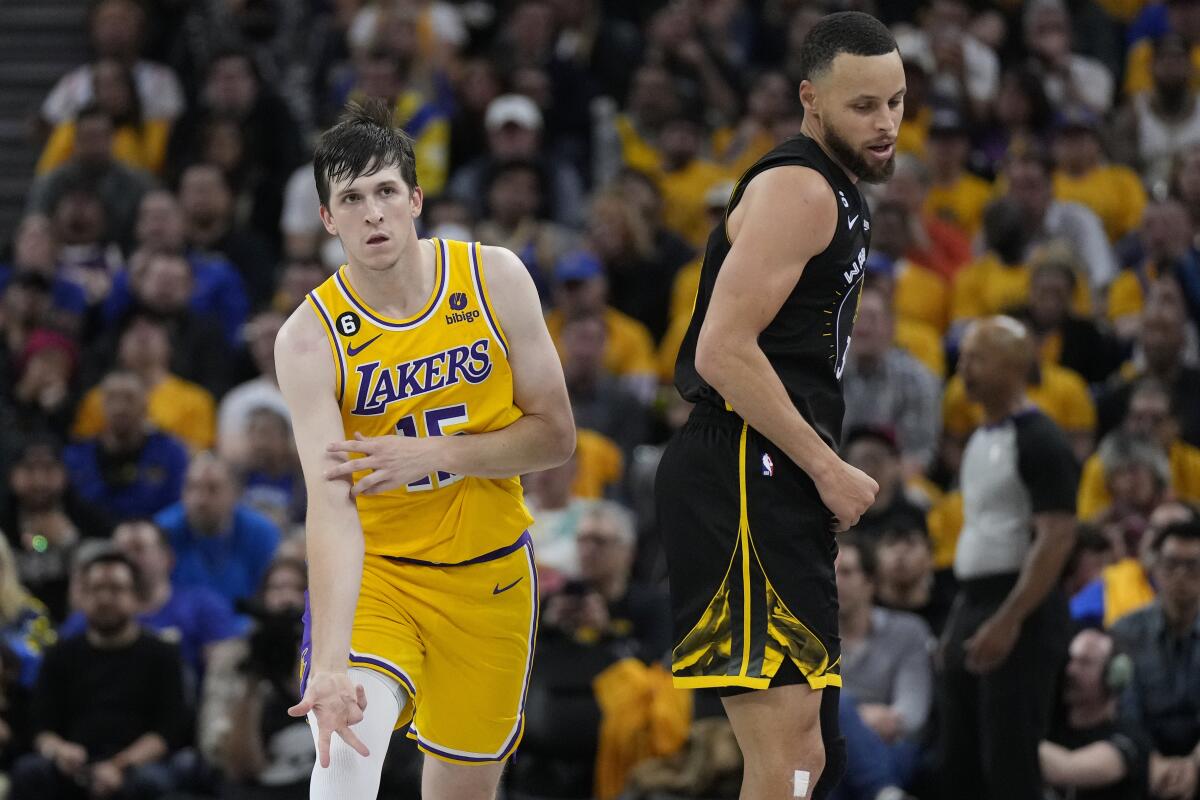 Lakers guard Austin Reaves celebrates with his ice-in-the-veins pose next to Warriors guard Stephen Curry during Game 1.