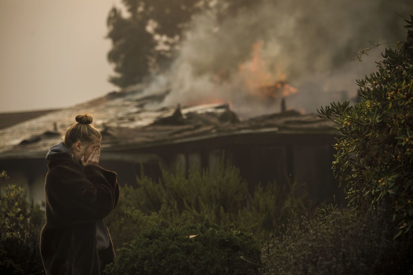 Olivia Jacobson, 16, wipes tears as she looks at her family's home, destroyed by the brush fire on Island View Drive in Ventura.
