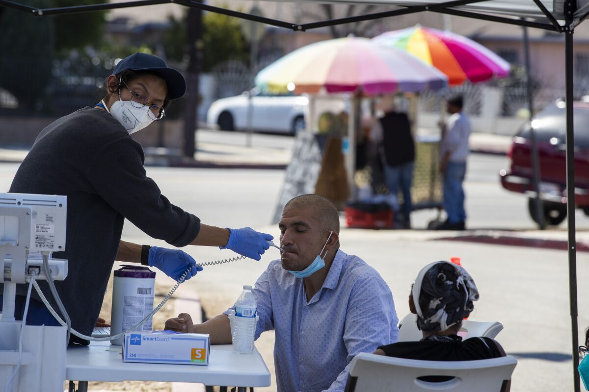 A man sitting outside gets his temperature taken.