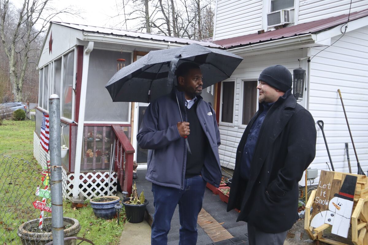 Environmental Protection Agency Administrator Michael Regan, left, speaks with Eddie George, an employee for the non-profit DigDeep, outside the home of Rose Runyon in Premier, W.Va., on Tuesday, Dec. 6, 2022, during a visit to McDowell County to speak with residents about safe water and wastewater access. (AP Photo/Leah Willingham)