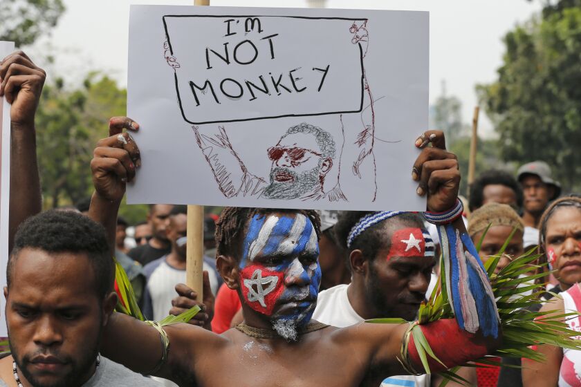 A Papuan students with faces painted with the colors of the separatist 'Morning Star' flag holds up a poster during a rally near the presidential palace in Jakarta, Indonesia, Wednesday, Aug. 28, 2019. A group of West Papuan students in Indonesia's capital staged the protest against racism and called for independence for their region. (AP Photo/Tatan Syuflana)