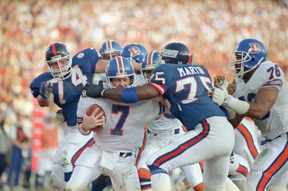 Denver Broncos quarterback John Elway gets sacked for a safety by New York Giants left end George Martin.