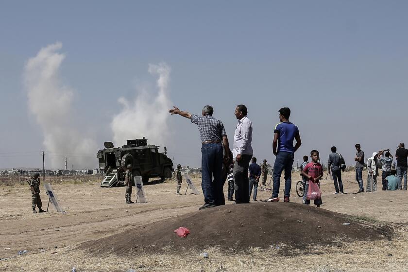 People standing on the Turkish side of the border with Syria, on the outskirts of Suruc, Turkey, watch as smoke rises over Kobani, in Syria, on Saturday.