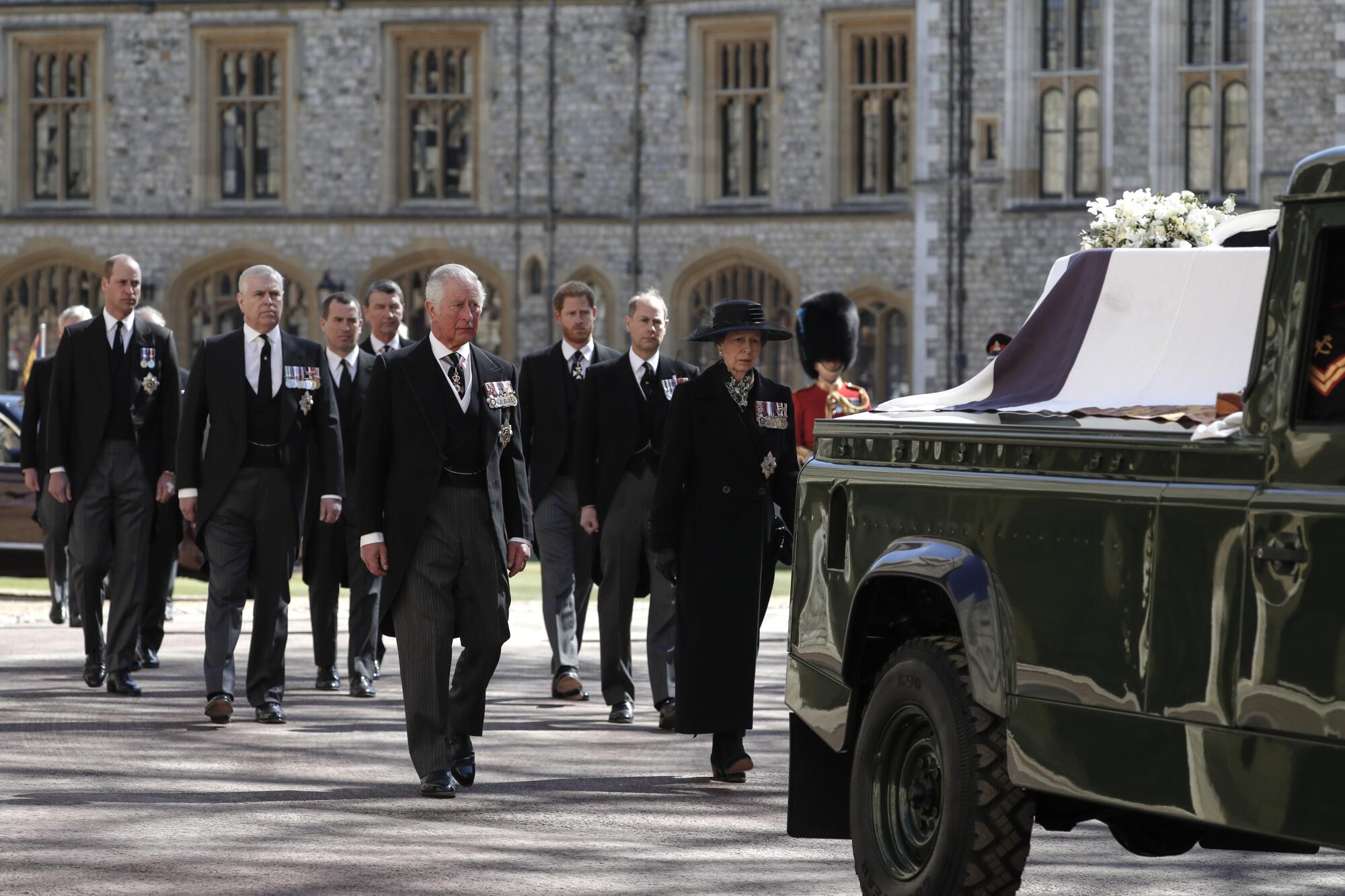 Members of the royal family walk behind Prince Philip's coffin resting in a modified Land Rover in a procession.