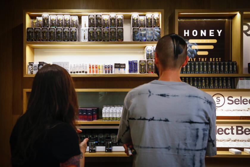 Tina Glen (left) and Nick Isordia look at the vaping products at March and Ash, a cannabis dispensary in Mission Valley.