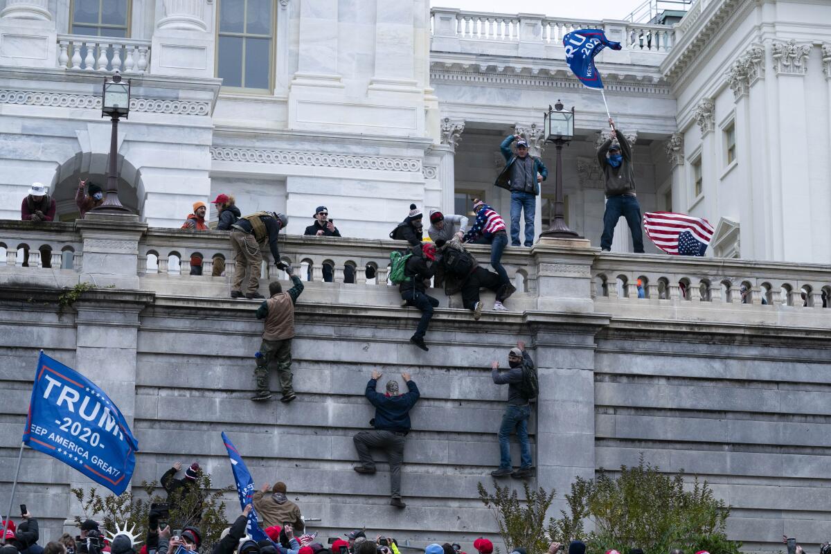 Supporters of President Trump climb the west wall of the the U.S. Capitol
