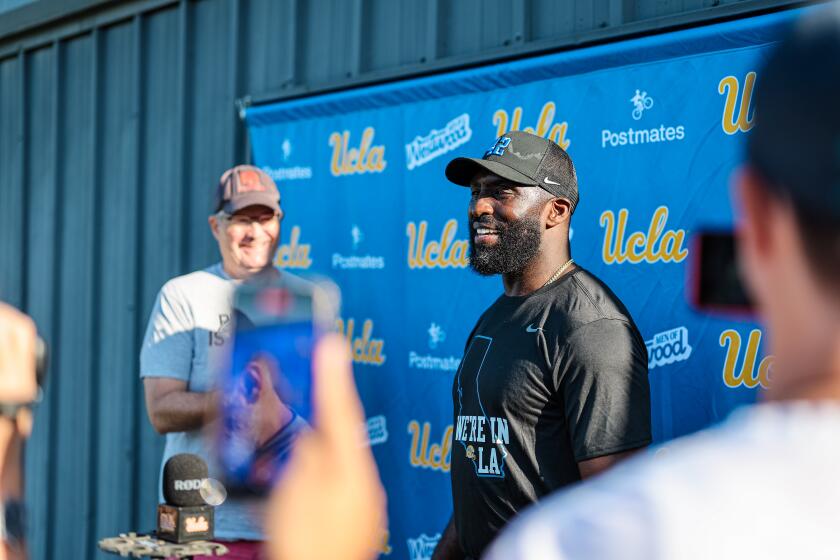 UCLA coach DeShaun Foster wears a shirt that reads, "We're in L.A.," while speaking with reporters