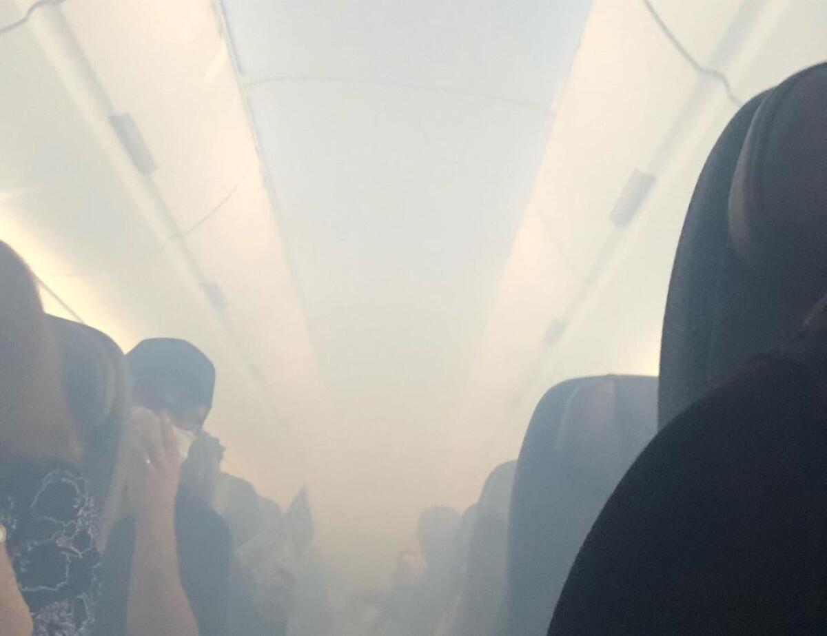 Passengers on a Hawaiian Airlines flight cover their noses as the cabin fills with smoke. 
