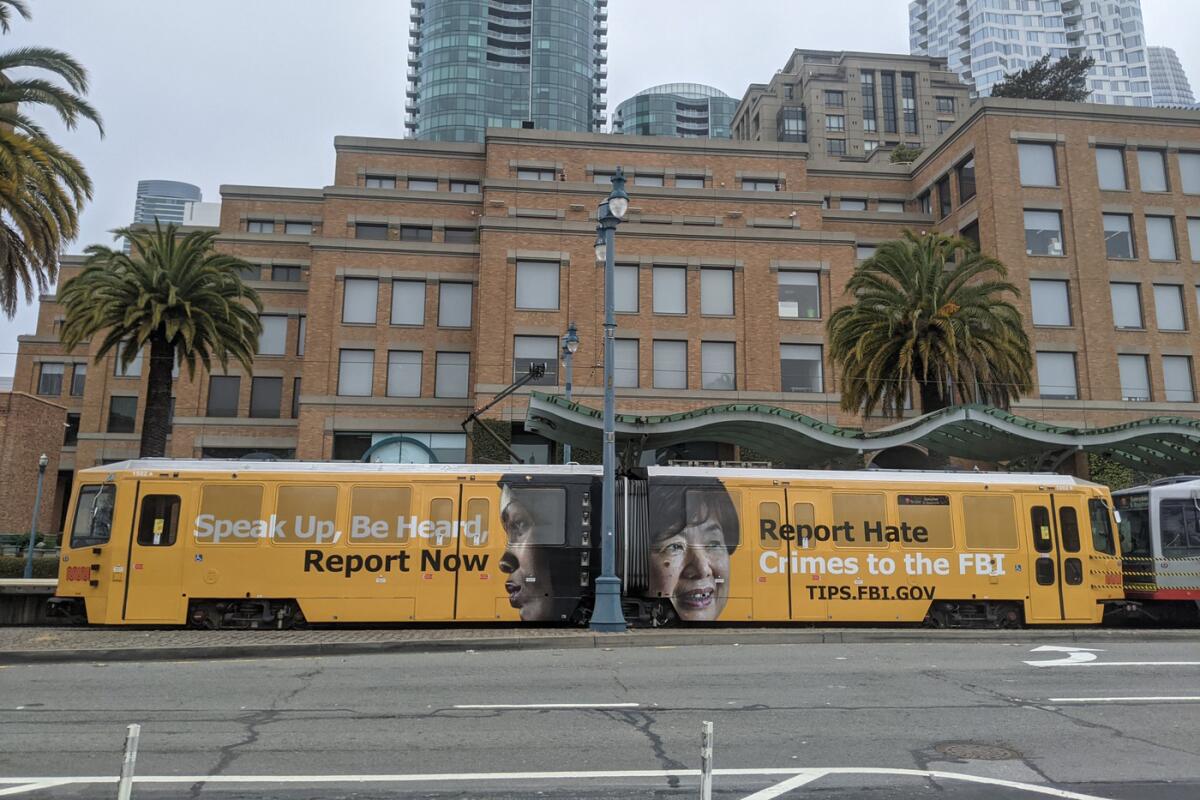 A San Francisco city train reads "Speak Up, Be Heard, Report Now. Report Hate Crimes to the FBI." 