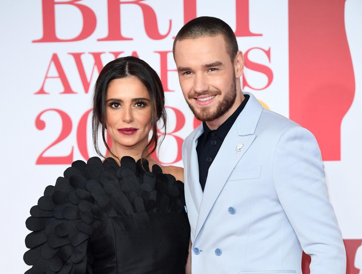 Cheryl Cole in a black gown poses with Liam Payne in a blue suit