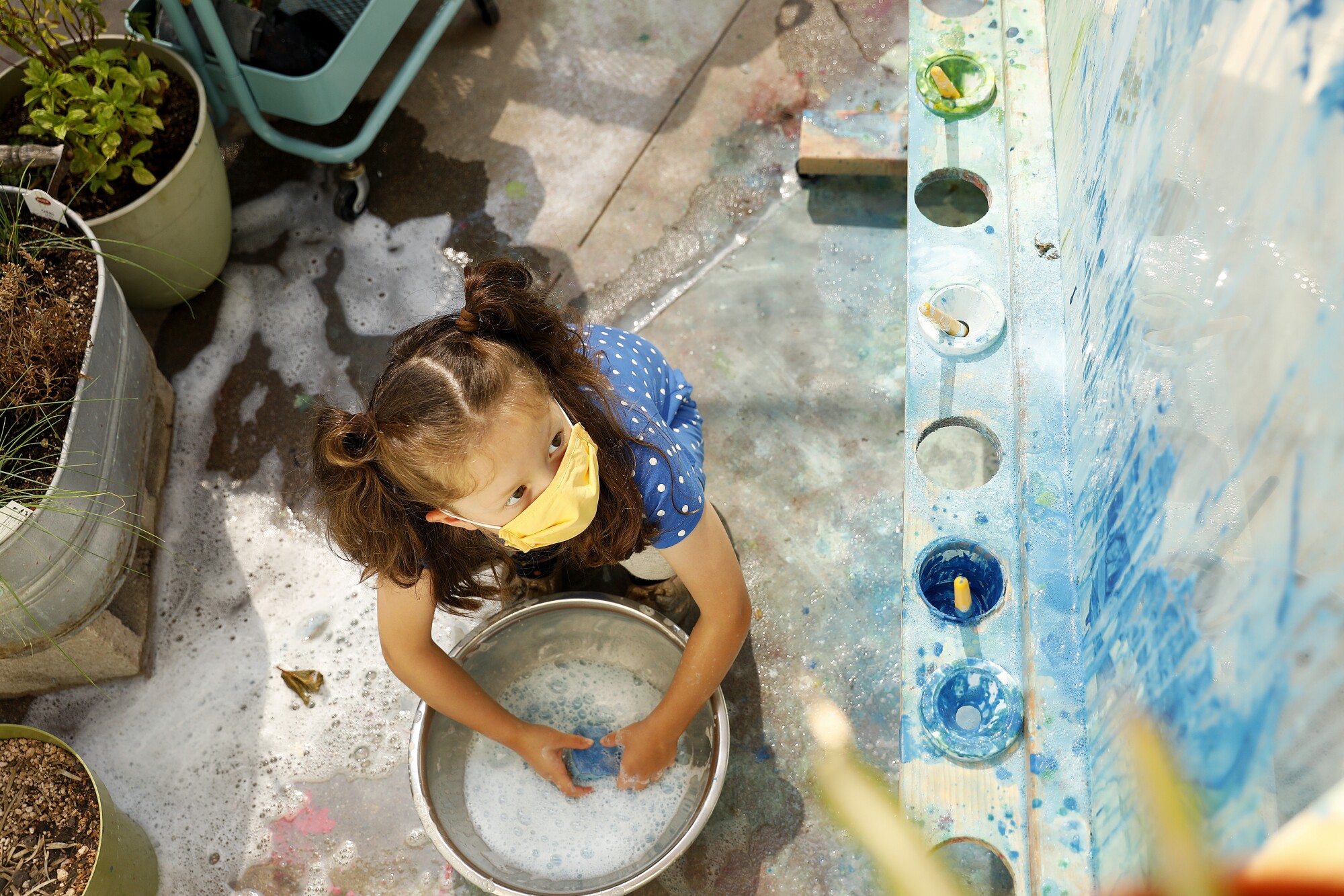 A child wears a mask while painting at Voyages Preschool in Los Angeles.